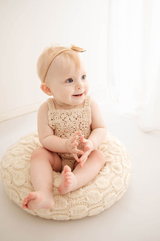 six month old baby smiling at her studio photoshoot in New Malden