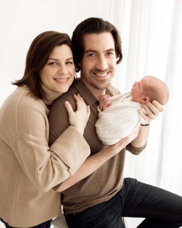 mother and father proudly hold baby at photoshoot in Epsom