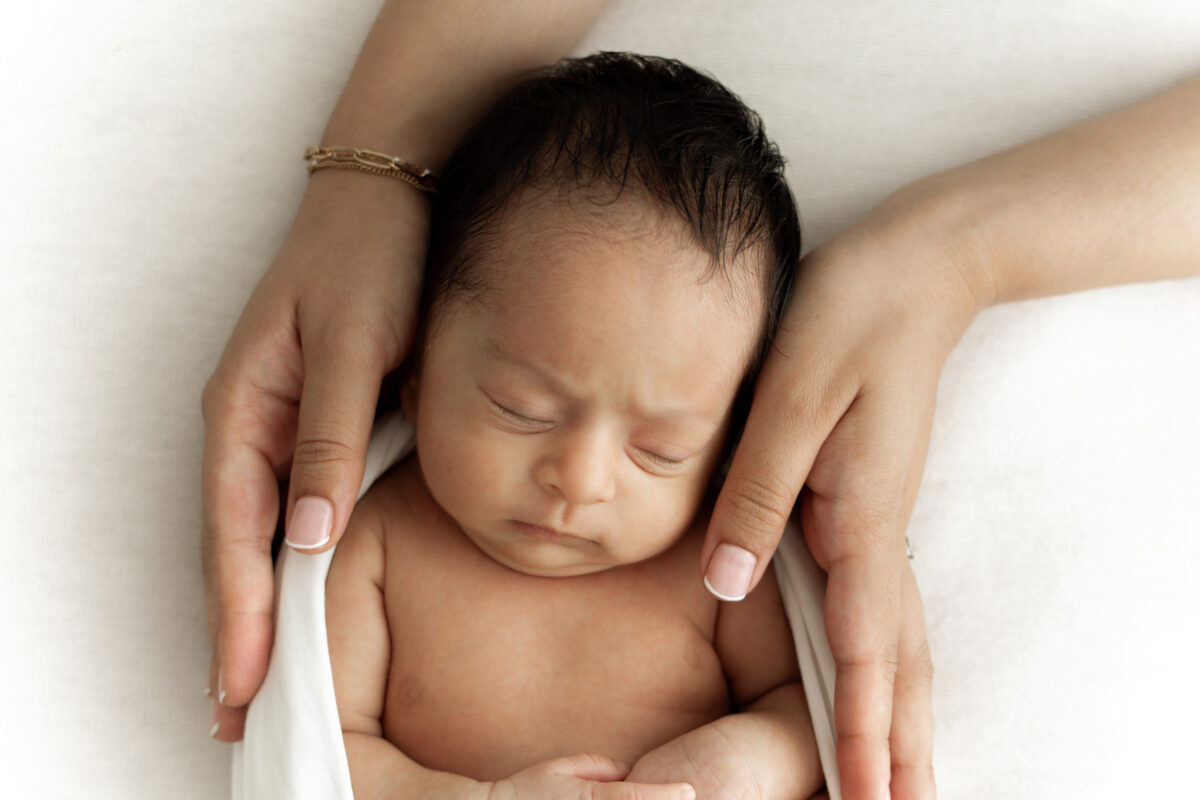 baby sleeping peacefully in mothers hands at newborn photoshoot in Kingston Upon Thames